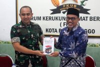 Ketua FKUB Ahmad Hudri menyerahkan kenang-kenangan sebuah buku ke Letkol Arh Iwan Hermaya. Foto: suarabhinneka.id