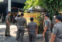 Petugas Satpol PP memasang papan pemberitahuan penutupan sementara mie Gacoan Kota Probolinggo. Foto: suarabhinneka.id